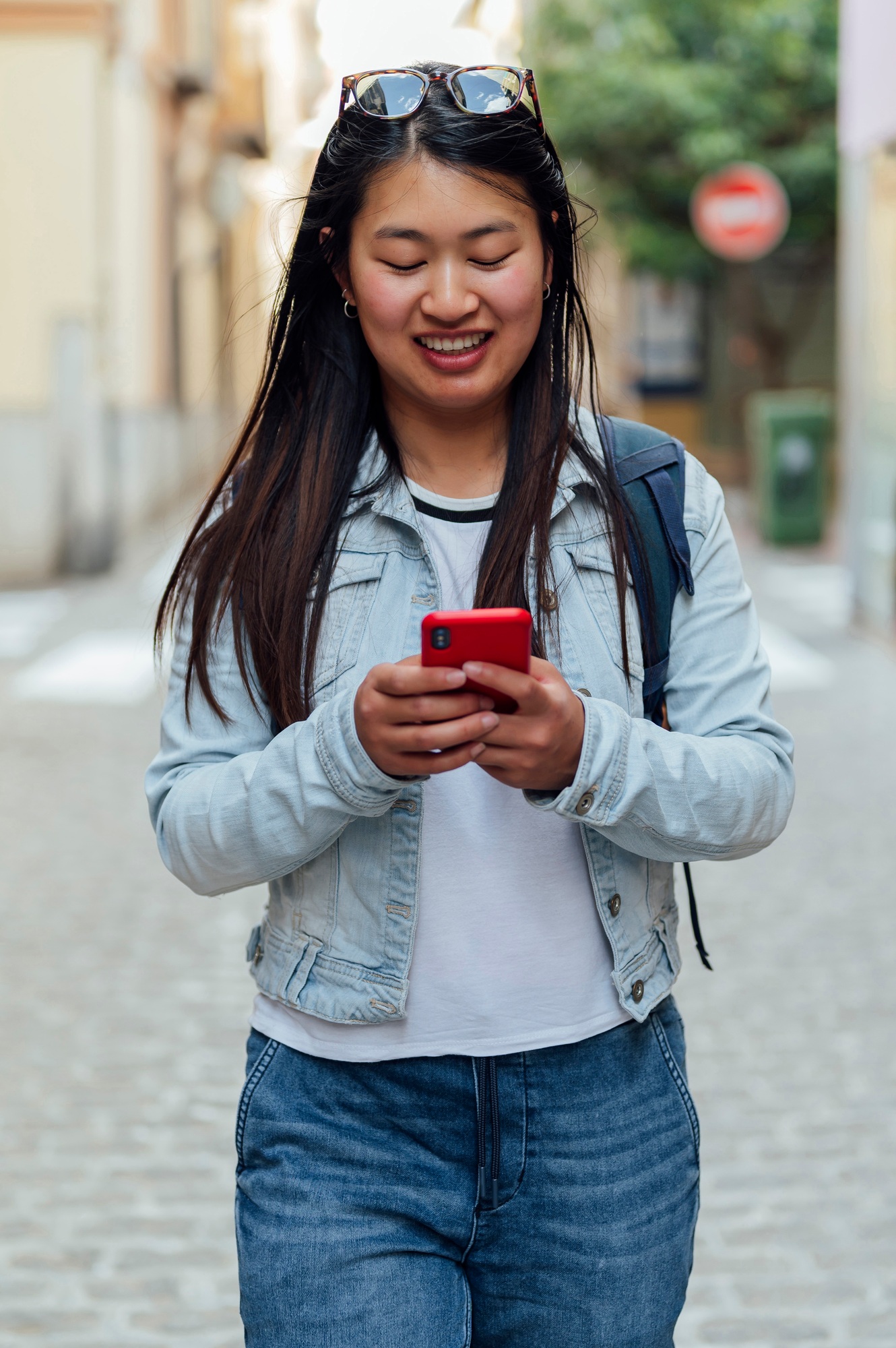 Asian woman typing with mobile phone in the street